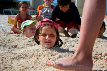 girl buried up to neck in the sand at beach